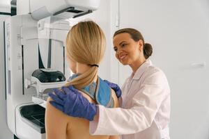 Smiling doctor prepairing woman before doing mammogram x-ray to check for breast cancer at hospital photo