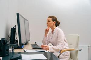 Focused professional doctor radiologist analyzing scan MRI images on computer in medical center photo