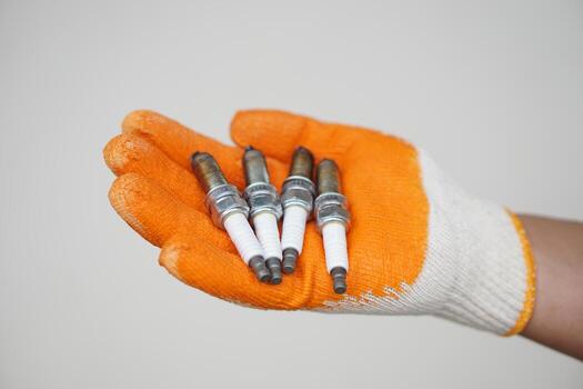 Close up mechanic hands hold old spark plug, spare part of car engine. Concept, machine maintenance, fix, repair, check or diagnose automobile problems by engine specialist. photo