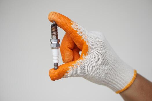 Close up mechanic hands hold old spark plug, spare part of car engine. Concept, machine maintenance, fix, repair, check or diagnose automobile problems by engine specialist. photo