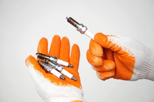 Close up mechanic hands hold old spark plug, spare part of car engine. Concept, machine maintenance, fix, repair, check or diagnose automobile problems by engine specialist. photo