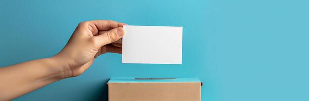 Voting Concept Hand Holding Blank Card Over Ballot Box on Blue Background, Suitable for Elections, Democracy, and Political Campaigns photo