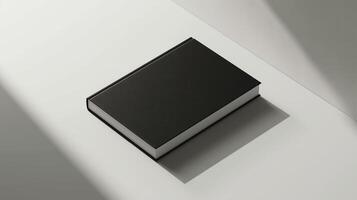 Black book on a white table with a shadow. Minimalist book mockup with a plain cover and copy space for text, suitable for graphic design presentations and publishing concepts. photo