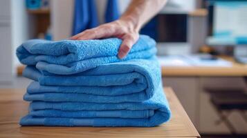 Hand Folding Blue Towels in Household Setting with Background of Office Space, Perfect for Home Organization and Cleaning Themes, Bright and Clean Look for Domestic Chores and Laundry Concepts photo