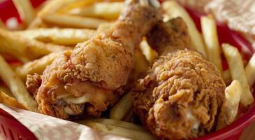 Crispy Fried Chicken Drumsticks With Golden French Fries in Red Basket, Perfect Comfort Food, Close-Up Shot, Ideal for Fast Food Menus and Advertisement, Tantalizingly Delicious and Irresistible photo