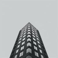 Monochrome image of a modern skyscraper from a low-angle perspective, showcasing geometric architecture and urban design. Ideal for corporate, architectural, and real estate concepts. photo