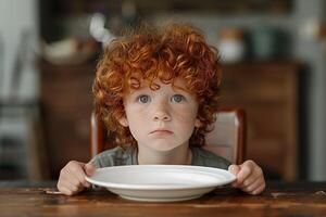 Adorable Redheaded Child with Freckles Holding Empty Plate, Waiting for Food in Rustic Kitchen Setting with Warm Lighting, Childhood Innocence, Homey Atmosphere photo