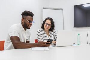 Two Colleagues Collaborating on a Project Using Laptop and Smartphone in a Modern Office photo