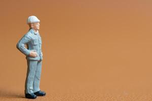 Miniature construction worker. A man dressed in a blue work uniform, complete with a hard hat. He stands confidently with his hands on his hips photo