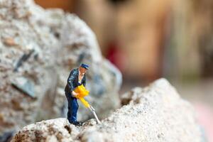 A miniature worker worker drilling a big rock . Themes of perseverance, strength and labor. photo