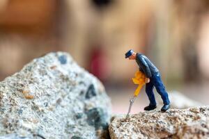 A miniature worker worker drilling a big rock . Themes of perseverance, strength and labor. photo
