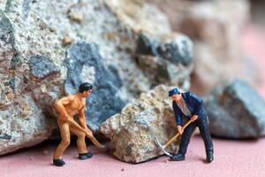 A miniature worker worker drilling a big rock . Themes of perseverance, strength and labor. photo