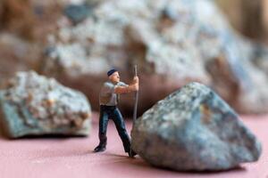Miniature worker pushing a large rock. Themes of perseverance, strength and labor. This makes it suitable for use in content that involves hard work, challenges, and overcoming obstacles. photo