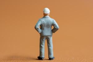 Miniature construction worker. A man dressed in a blue work uniform, complete with a hard hat. He stands confidently with his hands on his hips photo