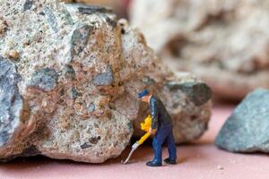 A miniature worker worker drilling a big rock . Themes of perseverance, strength and labor. photo