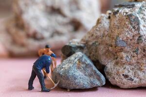 A miniature worker worker drilling a big rock . Themes of perseverance, strength and labor. photo