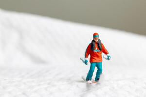 A miniature figurine of a skier dressed in vibrant winter gear. This image is perfect for themes related to winter sports photo