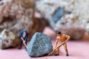 A miniature worker worker drilling a big rock . Themes of perseverance, strength and labor. photo