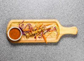 chicken joint bone bbq satay with chilli sauce served on wooden bard isolated on grey background top view of hong kong fastfood photo