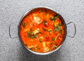 spicy tom yam soup with chicken served in broth isolated on grey background top view of hong kong fastfood photo