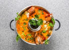 spicy tom yam soup with king shrimps served in broth isolated on grey background top view of hong kong fastfood photo