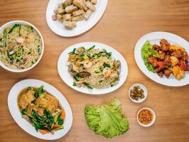 chinese seafood table Beancurd Kailan, Stir Fried yam, Xinghua Lor Mee, in a dish with chili sauce, and king's salad leaf top view on wooden background photo