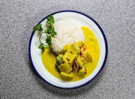 Yellow chicken curry with white rice, cucumber and coriander served in plate isolated on grey background top view of hong kong fastfood photo