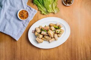 Stir Fried yam in a dish with chili sauce, and king's salad leaf top view on wooden background photo