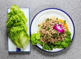 Minced pork salad with lettuce leaves, cucumber and coriander served in plate isolated on grey background top view of hong kong fastfood photo