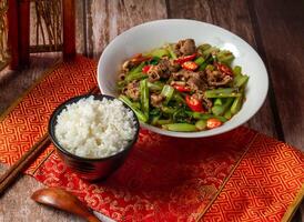 Shacha beef with white rice, vegetables, chopsticks and spoon served in dish isolated on napkin side view on wooden table of taiwanese food photo