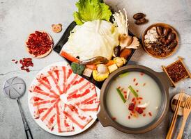 Clear soup pot set, cabbage, broccoli, mushroom, baby corn with red chilli, chopsticks and fork served in pot isolated on background side view of taiwanese food photo