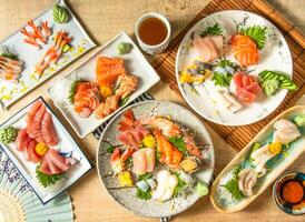 Assorted Comprehensive Sashimi with Dory sashimi, salmon sashimi, Tuna fish, swordfish, Sweet shrimp served in plate isolated on napkin top view on wooden background of Japanese food photo