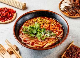 Hot and Sour Beans Noodles with coriander, red chilli, chopsticks and fork served in pot isolated on background side view of taiwanese food photo
