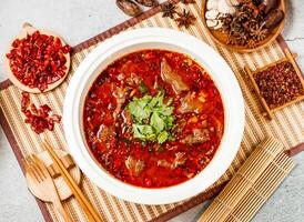 Spicy Boiled beef with coriander, red chilli, chopsticks and fork served in pot isolated on background side view of taiwanese food photo