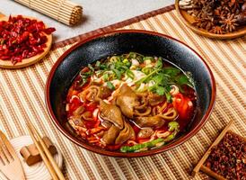 Braised pork sausage noodles with corinder, spring onion, red chilli, chopsticks and fork served in pot isolated on background side view of taiwanese food photo