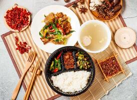 twice cooked pork, mice meat, white rice, soup with red chilli, chopsticks and fork served in pot isolated on background side view of taiwanese food photo