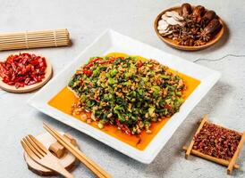 Snow red minced meat with red chilli, chopsticks and fork served in pot isolated on background side view of taiwanese food photo
