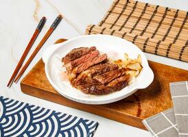 Grilled Sharon steak slice with chopsticks served in dish isolated on wooden board and napkin side view of taiwan food photo