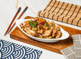 Sauteed Chicken with chopsticks served in dish isolated on wooden board and napkin side view of taiwan food photo