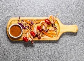 Jumbo Shrimp Ball Satay Skewers with chilli sauce served on wooden bard isolated on grey background top view of hong kong fastfood photo