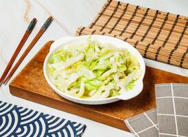 cabbage salad with chopsticks served in dish isolated on wooden board and napkin side view of taiwan food photo