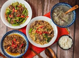 Beef fried noodles, Shacha Lamb, Stir fried beef with shredded ginger, Ginger mutton clear soup, boiled white rice with chopsticks and spoon served in dish side view on wooden table of taiwanese food photo