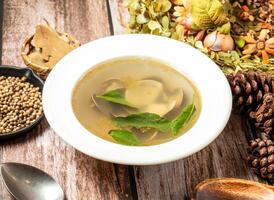 Clam consomme soup with spoon and fork served in plate isolated on wooden table side view of taiwan fasfood photo