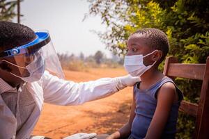 African doctor is busy visiting a young child who is about to take a serological test photo