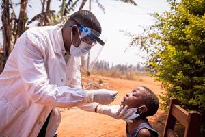 An african doctor does a swab test on a child to see if he positive to coronavirus. Covid-19 test in Africa. Molecular and rapid antigen test photo