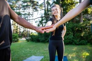 A group of people are holding hands in a park during a training class, concept of togetherness photo