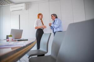 Two colleagues having conversation in office meeting room, age difference photo