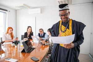 An African businessman analyzes charts during a meeting, his colleagues work in the background photo