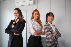 Three happy businesswomen with folded arms and confident expressions pose in the office photo
