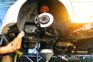 Car maintenance service concept , Car mechanic is repairing in the auto repair garage , bottom view of automobile suspension on a hydraulic car lift photo